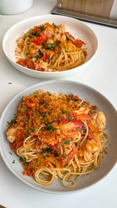 two plates of pasta with shrimp and tomato sauce