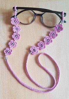 a pink crocheted lanyard with eyeglasses on the side and a pair of glasses