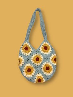 a crocheted bag with sunflowers on the front and bottom, hanging from a hook