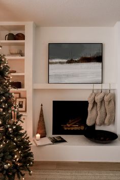 a christmas tree in front of a fireplace with stockings hanging from it's mantle