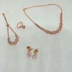 Elevate your style with this exquisite American Diamond CZ jewelry set in stunning rose gold. This set includes a necklace, bracelet, ring, and earrings, offering a complete and coordinated look for any special occasion. The intricate design and sparkling stones will make you the center of attention at weddings, parties, or formal gatherings. Product Details: Necklace: The centerpiece of this set, the necklace, features a dazzling American Diamond CZ pendant on a delicate rose gold chain. The adjustable chain allows you to find the perfect fit. Bracelet: The matching bracelet complements the necklace beautifully, with its American Diamond CZ stones set in a rose gold chain. It's designed to comfortably encircle your wrist and secure with a convenient clasp. Ring: The ring in this set showc Hand Set Round Jewelry Sets For Parties, Pink Jewelry Sets For Valentine's Day Party, Adjustable Pink Jewelry Set For Party, Rose Gold Metal Jewelry Sets For Party, Rose Gold Hand Set Jewelry Sets For Celebration, Hand Set Rose Gold Jewelry Sets For Celebration, Rose Gold Hand-set Round Jewelry Sets, Hand Set Rose Gold Jewelry Sets, Adjustable Round Jewelry Sets For Celebrations