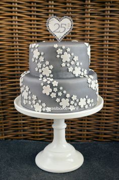 a three tiered cake with flowers on it sitting on a table next to a wicker basket