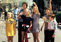 a group of people standing on the side of a road with their arms in the air