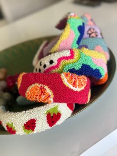 several knitted toys are sitting in a bowl on the counter top with rocks and pebbles