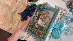 someone is holding an altered picture in front of a table with lace, beads and other items