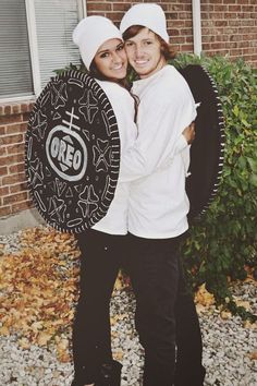 two people standing next to each other in front of a brick building holding a shield