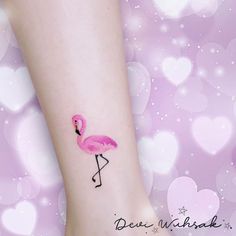 a small pink flamingo tattoo on the left side of the ankle, with hearts in the background