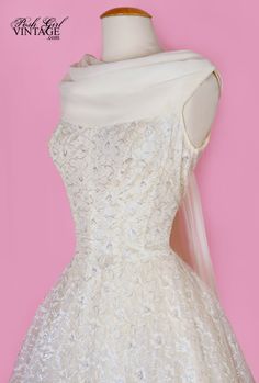 a white wedding dress on a mannequin with a pink wall in the background