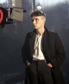 a man in a suit and tie standing next to a camera