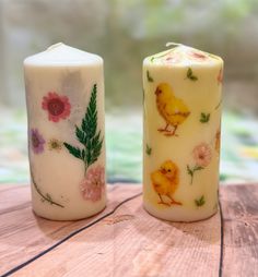 two candles with designs on them sitting on top of a wooden table next to each other