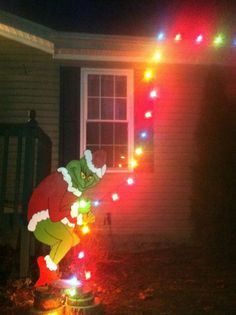 the grinch has been decorated with christmas lights and is standing in front of a house