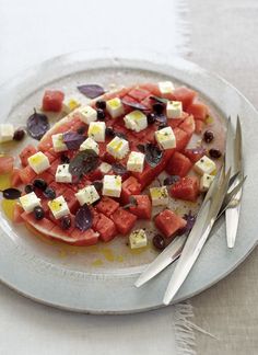 watermelon, olives and feta cheese on a plate with silverware