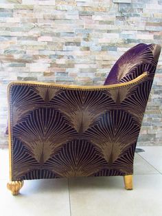 a purple chair sitting on top of a tile floor next to a brick wall and wooden legs