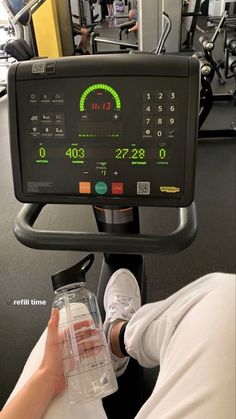 a person on a stationary exercise bike holding a water bottle in front of the monitor