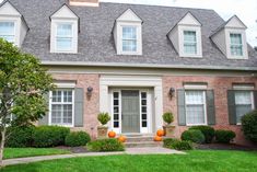 a brick house with green grass and pumpkins in the front yard