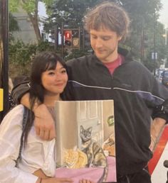 a man and woman standing next to each other holding an open book in front of them