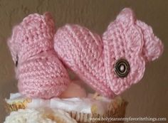 two pink knitted mittens sitting on top of a cupcake