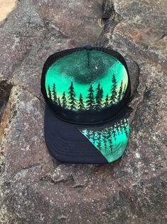 "One of a kind These are hand painted trucker hats, foam front and slight curved bill. They're made with fabric paint and sealed to protect from weather, I advise hand wash only to ensure a long life. They're adjustable SnapBack and work fo a 17-22\" head size. One of a kind! Mesh back*most hats are made to order and will differ slightly from listing photo" Hand Painted Snapback Hat, Hand Painted Adjustable Snapback Hat, Custom Handmade Hats For Outdoors, Artistic Hand-painted Cap, Artistic Hand Painted Cap, Green Trucker Hat For Festivals, Custom Snapback Baseball Cap For Outdoor, Custom Outdoor Trucker Hat With Snapback, Custom Outdoor Trucker Hat Snapback