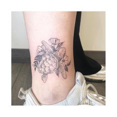 a woman's foot with a flower tattoo on the side of her leg,