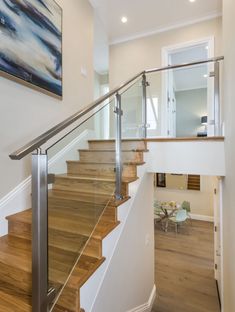 a staircase with glass railing and wooden handrail