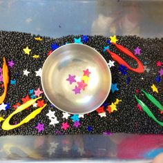 a metal bowl with scissors and stars on the floor next to other plastic objects that are scattered around it