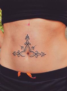 a woman's stomach with an intricate tattoo design on her lower back and side