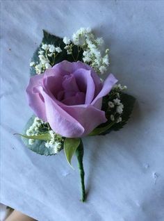 a purple rose and baby's breath boutonniere on a piece of paper