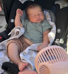 a baby sleeping in a car seat next to an air conditioner