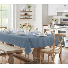 a dining room table with blue linens and white dishes on it in front of an oven