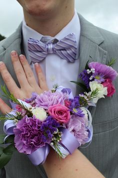 a close up of a person wearing a suit and tie with flowers on his arm