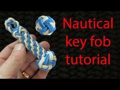 a hand holding a blue and white rope with the words nautical key fob on it