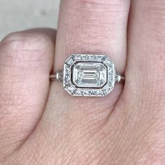 a woman's hand with an engagement ring on it, and the center stone is surrounded by diamonds