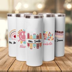 three personalized travel mugs on a wooden table