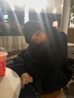 a woman sitting at a table with a drink in front of her