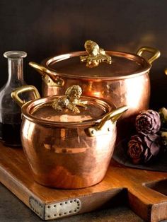 copper pots and pans are sitting on a wooden tray