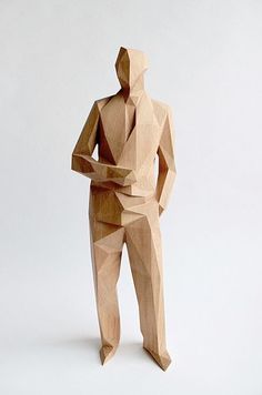 a wooden sculpture of a man holding an object in one hand and looking at the other