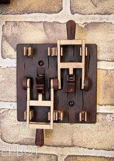 a clock made out of wooden pieces on a brick wall next to a light switch