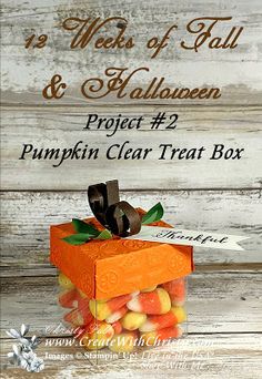 a pumpkin clear treat box filled with candies on top of a white wooden table