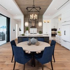 a dining room table with blue chairs and a chandelier hanging from the ceiling