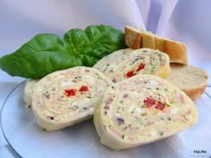 three slices of bread with meat and cheese on them next to spinach leaves, one slice has been cut in half