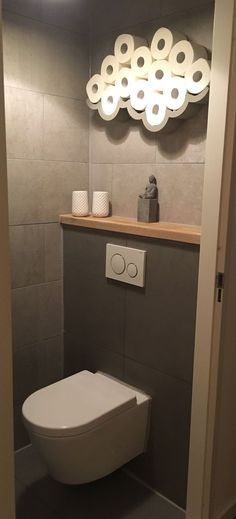 a white toilet sitting inside of a bathroom next to a counter top with rolls of toilet paper on it