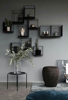 a living room with grey walls and black shelvings on the wall above a blue ottoman