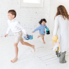 two children are running and playing in the room with white brick walls, while one child is holding a water bottle