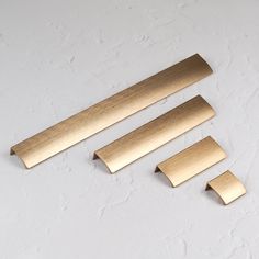 four pieces of brass metal on a white surface with space for the letter t to be cut out