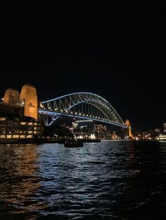 the sydney harbour bridge is lit up at night with lights reflecting off it's sides