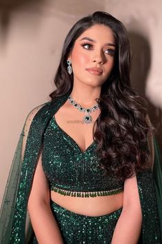 an image of a woman in a green dress with long hair and jewelry on her chest