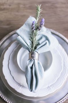 the napkin is on top of the plate with lavender flowers in it and silver rimmed dishes