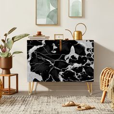 a black and white marble cabinet in a living room with gold accessories on the floor