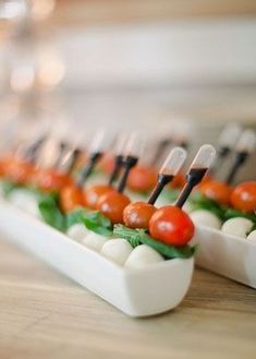 small appetizers with tomatoes, mozzarella and basil are lined up on a table