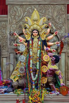 an elaborately decorated statue is displayed in front of a red curtain and wooden paneled wall